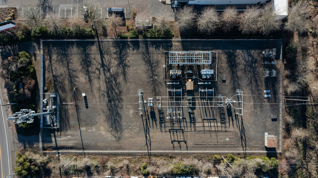 Aerial top down photo of an electric power substation with nearby cellular communication tower in Beaverton Oregon USA showing energy grid infrastructure utility equipment and telecom technology