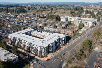 Fototapeta premium Aerial drone picture of a modern apartment complex in Beaverton, Oregon, with multi family residential buildings, surrounding neighborhood housing, streets, trees, and urban development 
