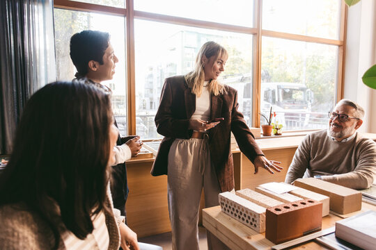 Female creative professional sharing design plan with colleagues in office