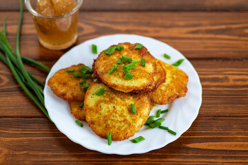 Traditional potato pancakes with fresh herbs on wooden table