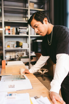 Focused male architect reading magazine while planning in office