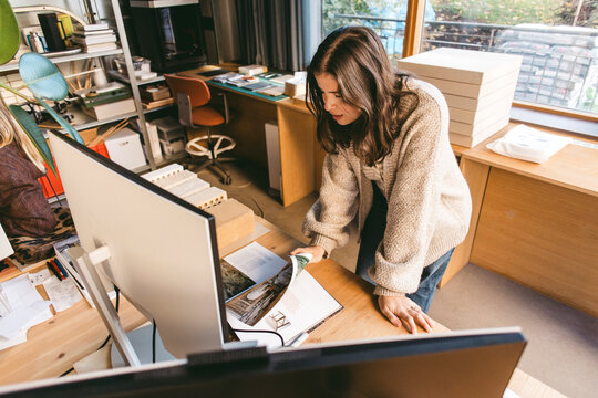 High angle view of female architect reading magazine while planning in office