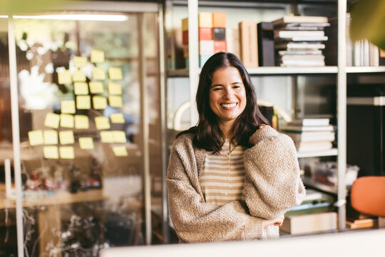 Smiling female business entrepreneur standing in front of computer at office
