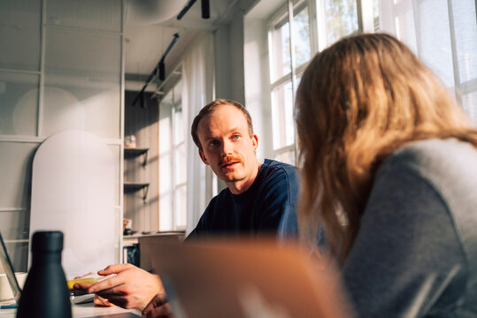 Businessman talking with female colleague in tech startup office