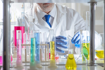 Experienced senior scientist working in a modern laboratory, carefully analyzing chemical samples among glass flasks and test tubes. Concept of chemistry expertise, scientific methodology © TSViPhoto