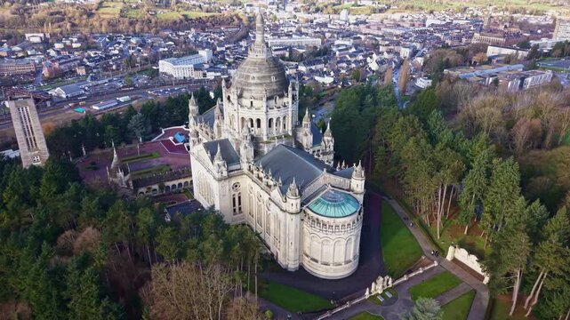 Drone descends toward Lisieux Basilica revealing nave and city backdrop