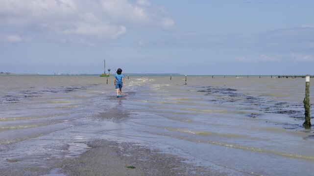 Boy walking into the water of the flooded street Passage du Gois.