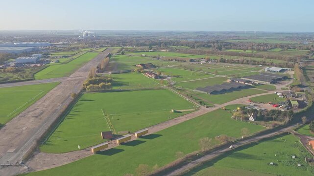 Aerial over the former RAF Winthorpe runway at Newark Air Museum in Nottinghamshire, revealing taxiways, service buildings, rural roads, and the flat agricultural landscape of the East Midlands.