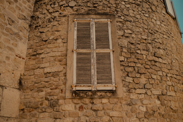 Vintage stone house wall with closed wooden shutters, rustic European architecture and historical building detail.