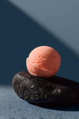 Minimal peach pink sorbet scoop on dark stone with dramatic light and modern food styling