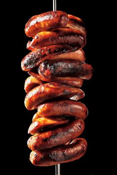 Pila de chorizos asados en brocheta fondo negro, Placer gourmet chorizos a la brasa de alta calidad, Fondo oscuro para publicidad de restaurante de carne premium