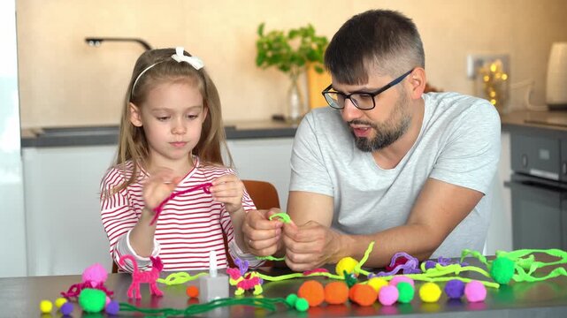 Father and little daughter make diy from colored chenille wire. Happy family create handmade craft. Leisure. Creative activities with children. Education