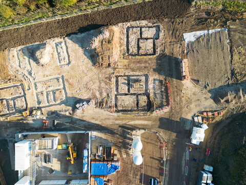 Drone top down view of new foundations for a housing development site in Britain. Note the mortar silos and building materials at the lower left of the image.