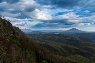 Obraz premium Hrensko, Czech Republic, Bohemian Switzerland National Park three years after a massive forest fire. The landscape shows dead tree trunks and active regeneration with new greenery under cloudy skies.
