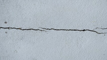 Gray or white concrete cracked house wall texture background. Cracks on the gray wall. That is not standard in construction. Crack in the concrete wall