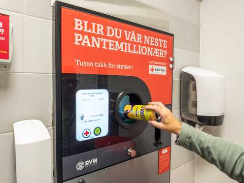 1 august 2025, Fistke, Norway.. Hand of a male customer putting recycable metal cans in a recycling machine at the entrance of a retail store in Norway. Environment, recycling theme.