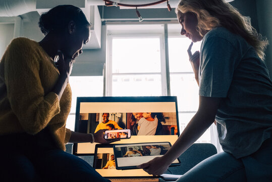 Low angle view of female tech experts discussing software design preview on different devices in office