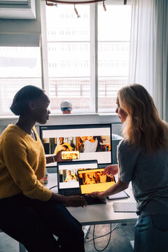 Female tech professionals discussing software design preview on different devices in office