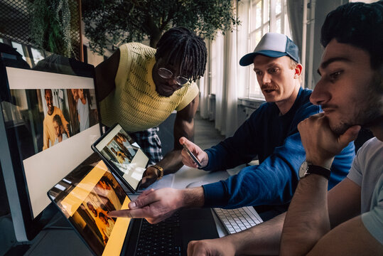Male creative tech professionals comparing responsive design preview on different devices in office