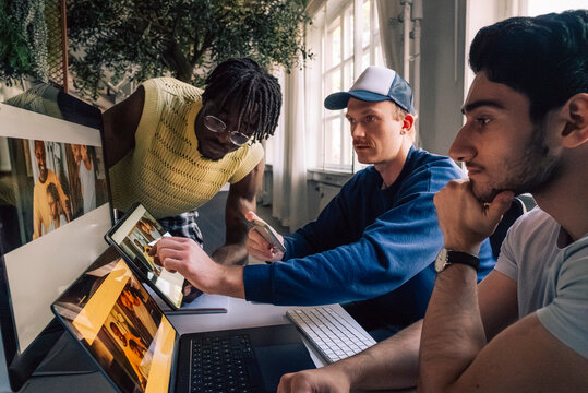 Male creative tech experts comparing responsive design preview on different devices in office