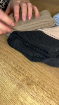 A woman examining a set of socks in different colors. Making a purchase review. Vertical video. Oblique Angle.