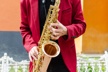 Naklejka premium An elegant musician playing a golden saxophone outdoors. Close up.