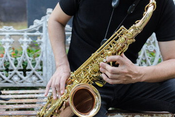 Obraz premium Authentic Musician Playing Golden Saxophone Instrument Outdoors on a Rustic Bench