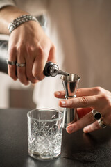 Barman pouring gin into glass at stylish bar counter. Emphasizes balance, precision, and purity of clear spirit preparation.