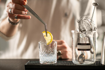 Close up of barman putting lemon slice into gin cocktail. Captures detail, clarity, and refreshing tones of the aromatic spirit.