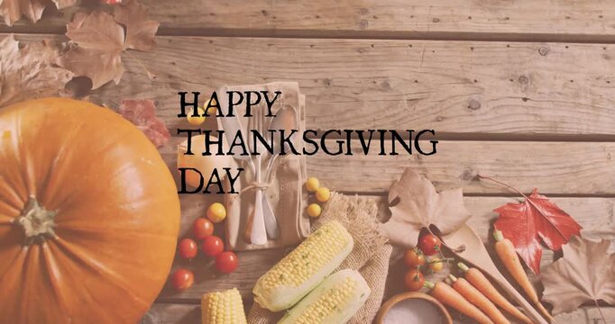 Animation of happy thanksgiving day text over autumn leaves and produce on wooden background