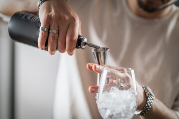 Bartender pouring whisky into shaker to make pineapple whisky sour. Captures flow, amber color, and...
