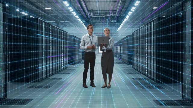 IT Analyst and Engineer Work in Data Center Using Laptop Standing In Warehouse, Activates Servers, Information Digitalization Starts. SAAS, Cloud Computing, Web Service. Graphics Visualisation