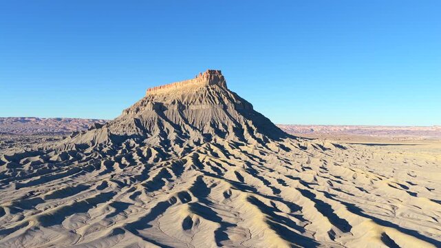 A drone captures the monochromatic grey ribs of the Mancos Shale. The ancient erosion at Factory Butte in Utah creates a skeletal, lunar landscape from a distant planet.