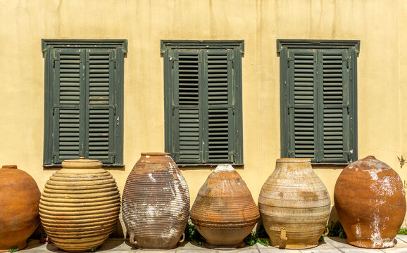 Traditional Greek Architecture with Large Terracotta Pithoi Jars and Green Louvered Shutters on Yellow Building Facade in Athens Greece
