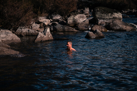 a man swims in the cold waters of a river in winter