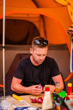 a man cooking in a camping ground next to a tent