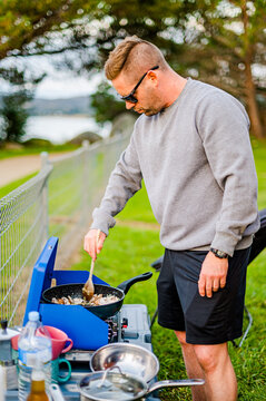 man on a camping setup making food on a gas stove