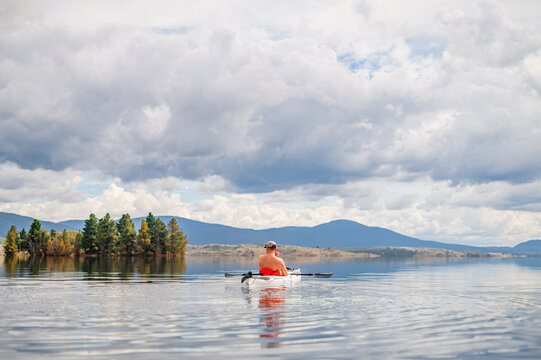 men on a kayak on a glassy lake during the day