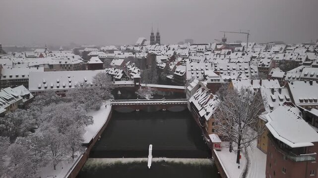 Aerial view on the historic old town of Nuremberg in Germany covered in snow during winter. The Pegnitz river in the foreground with Lorenzkirche in the back.