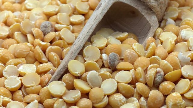 Macro shot of yellow split peas with wooden scoop, high-quality 4K food background for healthy plant-based protein marketing