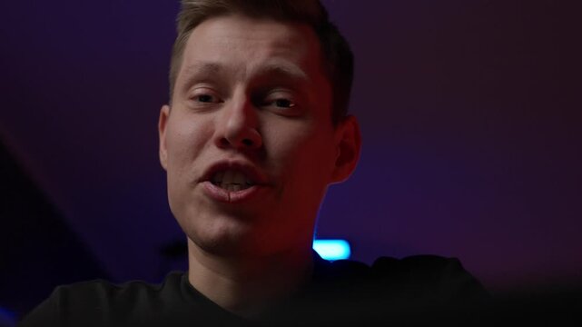 White Male Speaker Low Angle Closeup With Neon Backlight, Direct Address To Camera Delivering Testimonial And Persuasive Message, Warm Facial Expressions And Confident Tone, Cinematic Shallow Focus.