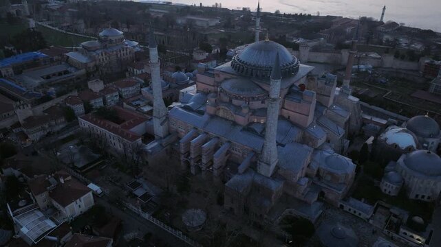 Aerial drone footage of Hagia Sophia (Ayasofya) in Istanbul, Turkey, captured at dusk. The iconic monument features its massive central dome, historic buttresses, and surrounding minarets, standing at