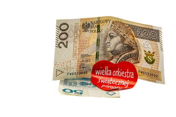 A 200 złoty banknote, a 50 złoty banknote, placed on a white tabletop with a red paper heart glued to it with the words Great Orchestra of Christmas Charity,fundraising,