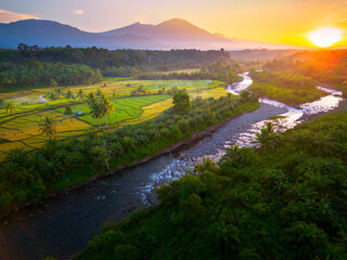 Beautiful morning view in Indonesia, panoramic landscape of rice fields with mountain ranges and clear sky