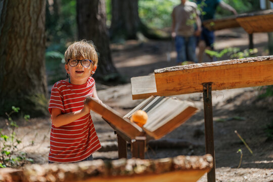 Child playing with Wooden marble run track in forest playground