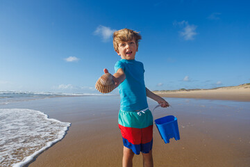 Boy happy holding seashell found on summer beach at vacations
