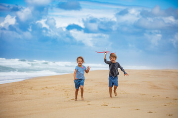 Children running, imaging, daydream with toy airplane on beach
