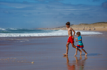 Two boys run joyfully along the beach on a sunny day of summer