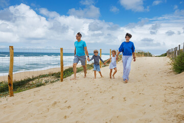 Family walking ocean beach path on sunny day at summer vacations