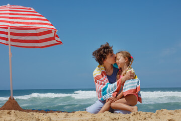 Mother and daughter share tender moment on hot day at the beach